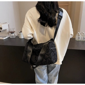Detail of black quilted cloud crossbody bag featuring wide adjustable strap on a model