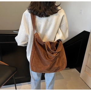 Detailed view of brown suede hobo bag worn by model showing texture and large capacity