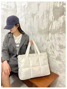 Side view of a large white quilted nylon tote bag with pearlescent finish on model
