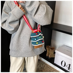 Détail du sac sapin de Noël au crochet vert avec pompons colorés et grand nœud rouge vif