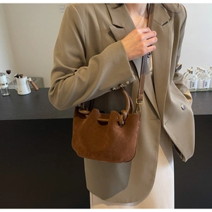 Detailed side view of a brown suede handbag with golden hardware and pleated design
