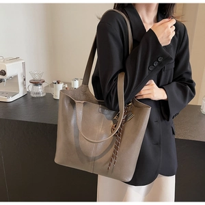 Close-up of taupe PU leather tote bag with braided strap detail on a commuter shoulder bag