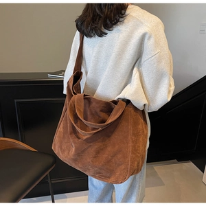 Detail of a large brown suede tote bag showing material texture and shoulder carry style