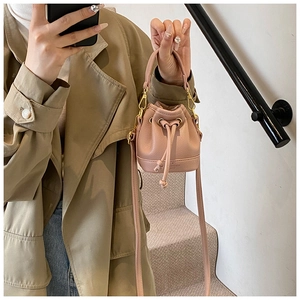 Détail du sac seau rose en cuir texturé avec cordon de serrage et mousquetons dorés