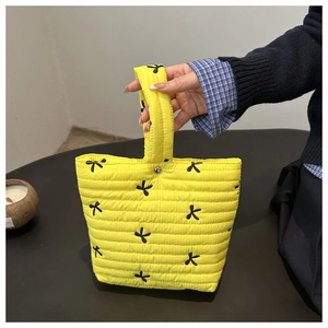 Detailed texture of yellow quilted pouch featuring embroidered black butterfly patterns