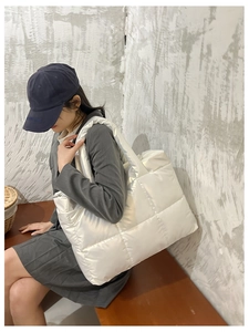 Detail of pearl white quilted puffer tote bag showing glossy texture and soft padding