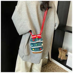 Détail d'un sac à bandoulière en tricot en forme de sapin de Noël avec pompons colorés