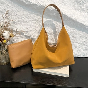 Set borsa hobo giallo zenzero con pochette coordinata su una superficie di legno