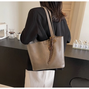Detail view of taupe PU leather tote bag with unique knot pendant and vertical stitching