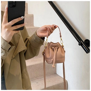 Détail du mini sac seau rose poudré en cuir grainé avec cordon et finitions dorées