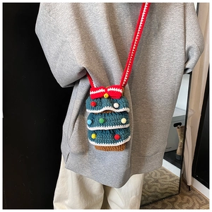 Détail du sac tricoté en forme de sapin de Noël avec nœud rouge et pompons