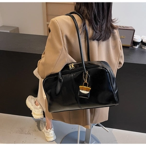 Detail of glossy black patent leather tote bag with gold hardware and shoulder straps