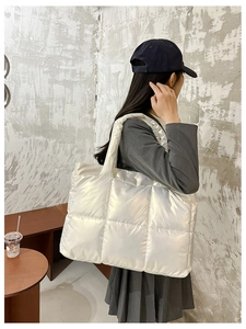 Detail view of large white quilted nylon tote bag with metallic finish and padded handles