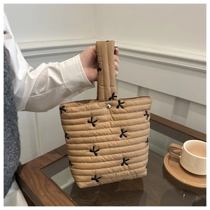 Detailed view of khaki quilted handbag featuring elegant black butterfly embroidery