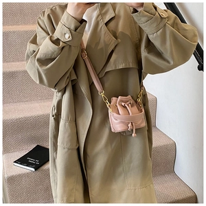 Détail d'un sac seau rose à cordon porté en bandoulière avec une bandoulière réglable