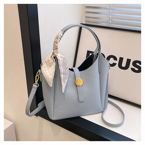 Chic light blue bucket bag with pebble leather texture and silk scarf wrapped handle