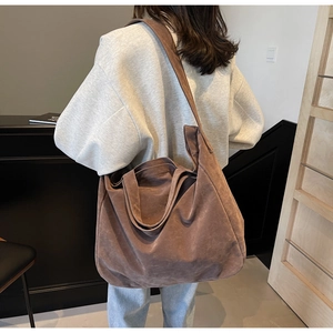 Close-up of brown suede oversized tote bag showing textured soft fabric and wide shoulder strap