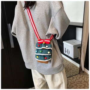 Détail d'un sac à bandoulière en crochet en forme de sapin de Noël avec pompons colorés