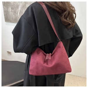 Detail of dark red suede underarm bag shown with a black trench coat for a chic look