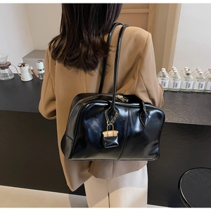 Detail of a black glossy PU tote bag with metal chain mini charm on shoulder strap