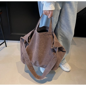 Macro view of mocha brown suede tote bag showing washed texture and wide shoulder strap