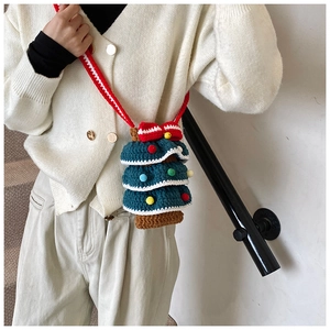 Détail du sac à bandoulière en tricot en forme de sapin de Noël avec pompons et nœud rouge