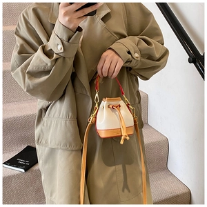 Gros plan sur le mini sac seau en cuir crème avec cordon de serrage et bords marron