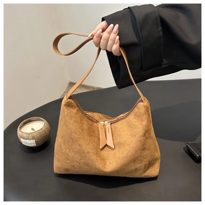Close-up of brown suede hobo bag with refined texture and long leather zipper pullers