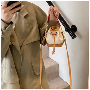 Détail du mini sac seau avec cordon de serrage en cuir blanc et lanières marron