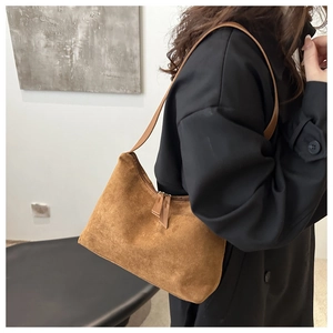 Detail of caramel brown suede baguette bag showing the zipper and slim shoulder strap