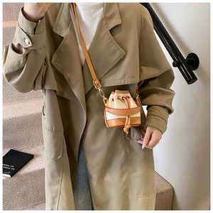 Détail d'un mini sac seau en toile avec finitions en cuir et boucles dorées porté croisé