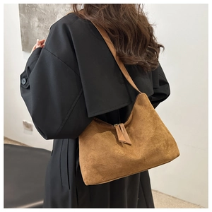 Brown suede hobo bag shown worn over a black coat highlighting texture and draped shape