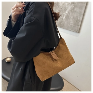 Detail of the brown suede hobo bag texture and slim leather shoulder strap on a model