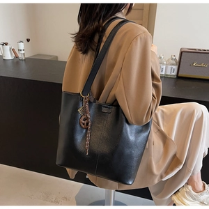 Detail of a black leather tote bag featuring stylish woven rope and resin bag accessories