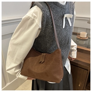 Close-up detail of the brown suede texture and smooth zipper on a stylish shoulder bag