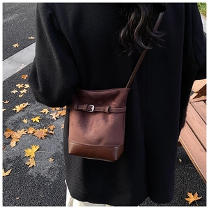 Brown frosted suede bucket bag shown from a back view on model in autumn park setting