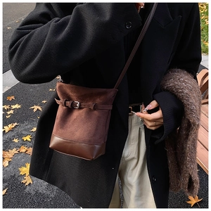 Detail of matte leather bucket bag with decorative buckle and dark brown contrast