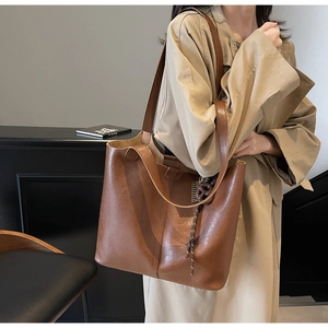 Brown vintage faux leather tote bag with a knotted charm shown on a model's shoulder