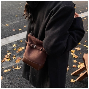 Close-up of brown frosted leather bucket bag with stylish belt buckle design details