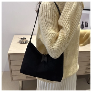 Detail view of a black suede-textured underarm bag featuring a dual zipper closure design