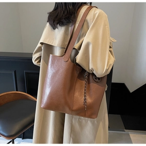 Close-up of brown PU leather tote bag with woven tassel detail and shoulder strap