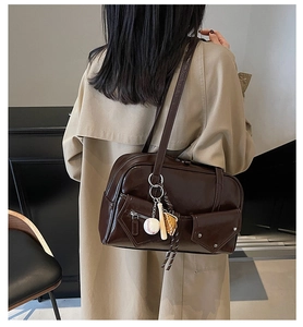 Détail d'un sac à bandoulière en PU marron foncé avec charme de baseball et poches