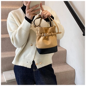 Detail of camel suede bucket bag with black leather bottom and adjustable strap