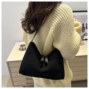 Detail view of black suede shoulder bag worn with warm autumn sweater and skirt