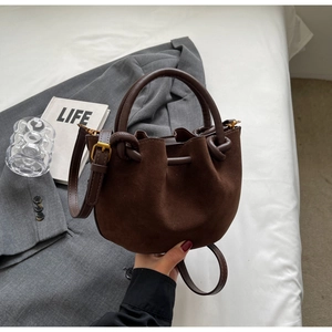 Retro brown suede bucket bag with leather handle and adjustable strap on white surface