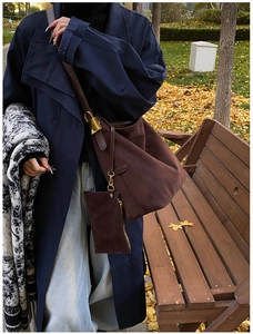 Close-up of brown suede shoulder bag with small zipper pouch and golden metal hardware