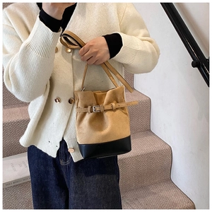 Detail of tan suede and black leather bucket bag with stylish belt buckle design