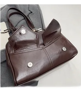 Vue de dessus d'un sac à main en cuir marron foncé avec boucles métalliques et poches frontales
