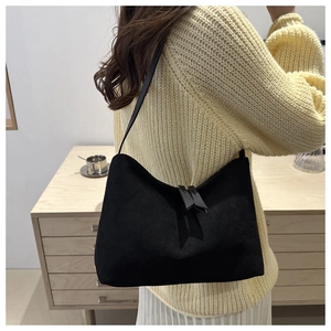 Close-up of black matte suede hobo bag with zipper tassels worn as a shoulder bag