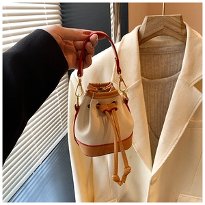 Mini sac seau crème avec base orange et poignée rouge pour filles sur un cintre